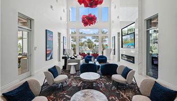 A lounge area with blue chairs and tables and large windows